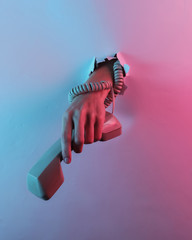 Wall Mural - Hand wrapped in a cable holds the handset through torn hole. Creative pop art pink blue neon color. Trendy gradient illumination. Night light