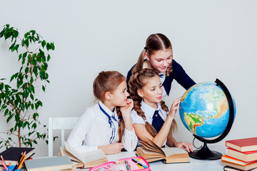 Wall Mural - three girls in the school geography lesson learn globe knowledge