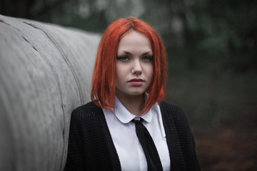 Portrait of the red-haired girl. The girl in a tie. Looks into the camera.