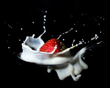 A Strawberry Falling Down Onto A Spoon And Splash Into Milk  Or Cream - Black Background