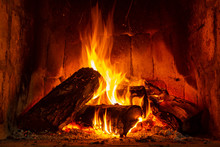 Fire In A Fireplace With Logs And Flames Creating A Sense Of Warmth And Coziness.