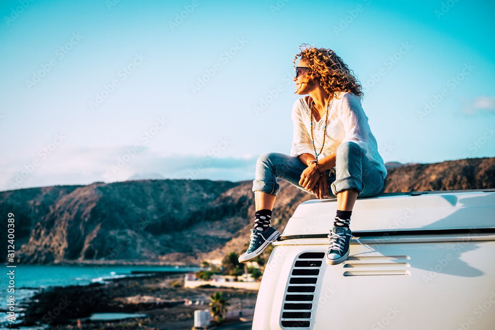 Travel concept with independent people enjoyig the outdoor leisure activity and wanderlust life lifestyle - woman sit down on the roof of a old nice vintage camper van - obrazy, fototapety, plakaty 