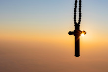 Silhouettes Of Crucifix Necklace Symbol With Bright Sunbeam On The Colorful Sky Background