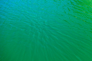 Wall Mural - aerial view of the texture of the surface of turquoise water with sun reflections