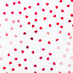 grey background with red glitter heart confetti. valentine day concept. trendy minimalistic flat lay