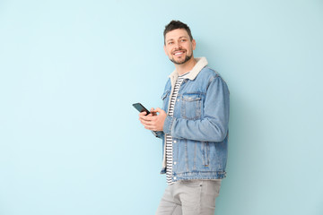 Happy man with mobile phone on color background