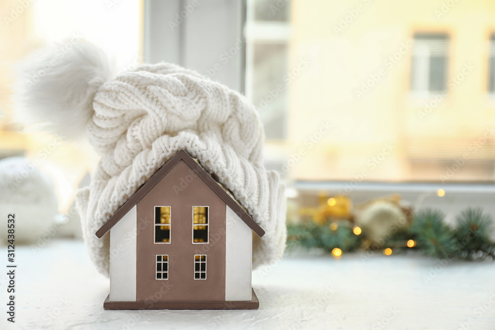 Model of house with hat on window sill. Winter concept