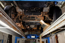 The Bottom Of The Car Lifted On A Lift Covered With Brown And Orange Rust During Anti-corrosion Treatment. Auto Service Industry.