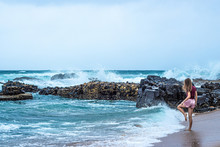 A Young Blonde Girl Watches The Crashing Waves Along The Ballito Coastline In South Africa