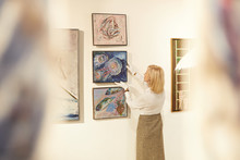 Back View Portrait Of Female Art Expert Hanging Paintings While Working In Art Gallery Or Museum, Copy Space