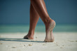 female legs on white beach with travel accessories, exotic vacation, product photo for travel agency