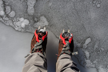 Two hiking boots with crampons on the ice. Mountain sport accessories concept