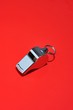Metal whistle on red background