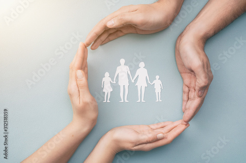 Fotografía Family care concept. Hands with paper silhouette on table.