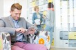 © MDBPIXS - Businessman using tablet PC with colleagues discussing in background at creative office