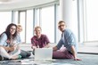 © MDBPIXS - Happy businesspeople looking away while working on floor at creative office