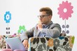 © MDBPIXS - Mid-adult businessman using laptop on armchair in creative office