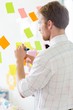 © MDBPIXS - Rear view of businessman writing on sticky paper at creative office