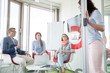 © MDBPIXS - Business people looking at female colleague standing in sliding door
