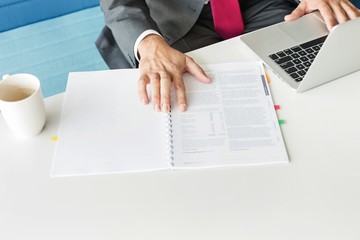 Wall Mural - Cropped image of businessman with book and laptop at desk