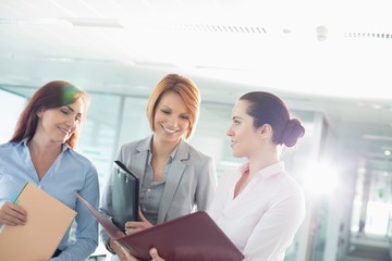 Wall Mural - Businesswomen with file folders discussing in office