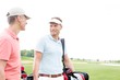 © MDBPIXS - Happy golfer communicating with male friend against clear sky