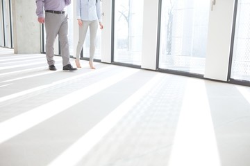 low section of business people walking by windows in empty office