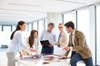© MDBPIXS - Male and female design professionals having discussion at table in new office
