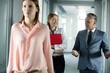 © MDBPIXS - Businessman and businesswoman talking while walking in corridor with female colleague in foreground at office