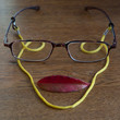 Faccia. Composizione con occhiali foglia rossa e laccetto giallo