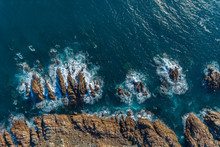 Aerial View Of Waves Crashing Into Rocky Cliffs Offshore