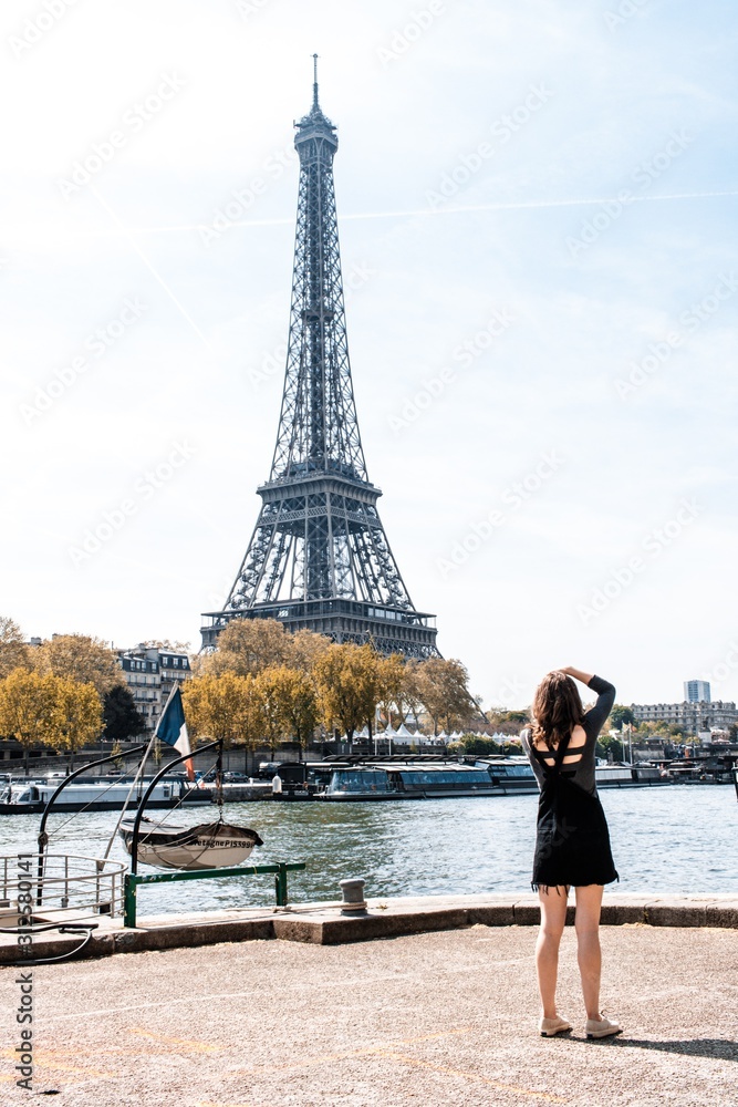 Woman taking a picture of the Eiffel Tower - obrazy, fototapety, plakaty 