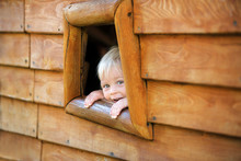 Curious Child, Toddler Boy, Peering From A Small Window In Wooden Shrub