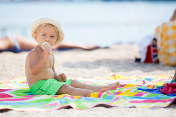 Wall Mural - Sweet blonde toddler boy, eaiting ice cream on the beach