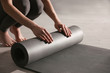 © New Africa - Woman rolling yoga mat in studio, closeup