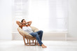 © New Africa - Attractive man relaxing in papasan chair near window at home. Space for text
