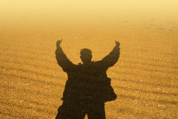 The shadow of a happy man is grafted on the floor of a yellow grain.