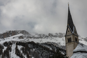 Wall Mural - Church steeple with snowy mountain and clouds in Italy