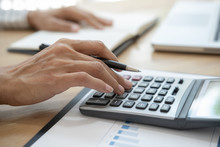 Close-up Of Business Woman Hand Using Calculator To Calculate Business Data, Accountancy Document At Home Office.