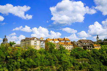 Wall Mural - green city living apartments ecology concept district in Europe urban landmark picture with buildings above trees foliage summer time blue sky white clouds background empty copy space for your text