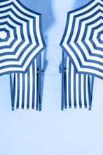 Top View Of Striped Chairs Under Umbrellas On Beach. Toning In Trendy Color 2020 Classic Blue.