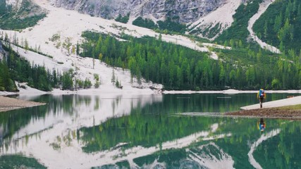 Wall Mural - young tourist hiker man at beautiful alpine lake lago di braies (pragser wildsee) in trentino. exult