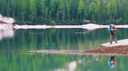 Wall Mural - young tourist hiker man at beautiful alpine lake lago di braies (pragser wildsee) in trentino. exult
