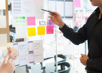 Young graphic designers are drawing the layout of the program for mobile phones.