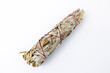 Unburned white sage smudge stick tied with white and red string isolated on white background horizontal in middle of frame. 