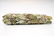 Unburned white sage smudge stick tied with white and red string isolated on white background horizontal in middle of frame. 