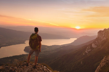 adventure travel with backpack, hiking outdoor in alps near annecy lake, man standing on top of moun