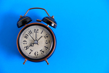 Old, vintage retro alarm clock on a bright blue background.