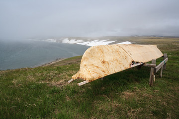 Arctic landscape with a boat on the shores of the Bering Sea. Baidara is a traditional leather boat of the Chukchi and Eskimos. Used by sea hunters to hunt walruses and whales. Chukotka, Russia.