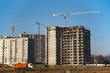 © MaxSafaniuk - Hydraulic luffing jib tower cranes and workers being poured concrete into foundation. Cement pouring into formwork of building at construction site. Tower cranes constructing a new residential build